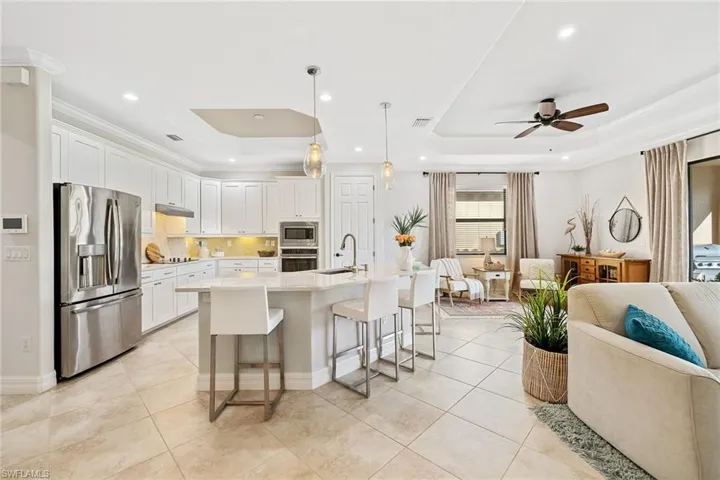 Kitchen featuring ceiling fan, white cabinets, appliances with stainless steel finishes, and a tray ceiling