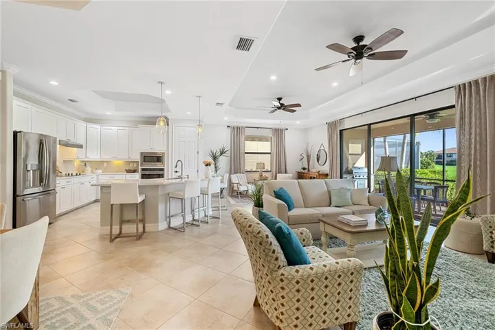 Living room featuring sink, ceiling fan, a raised ceiling, and light tile patterned floors