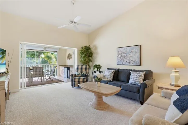 Spacious living area featuring a vaulted ceiling and a ceiling fan