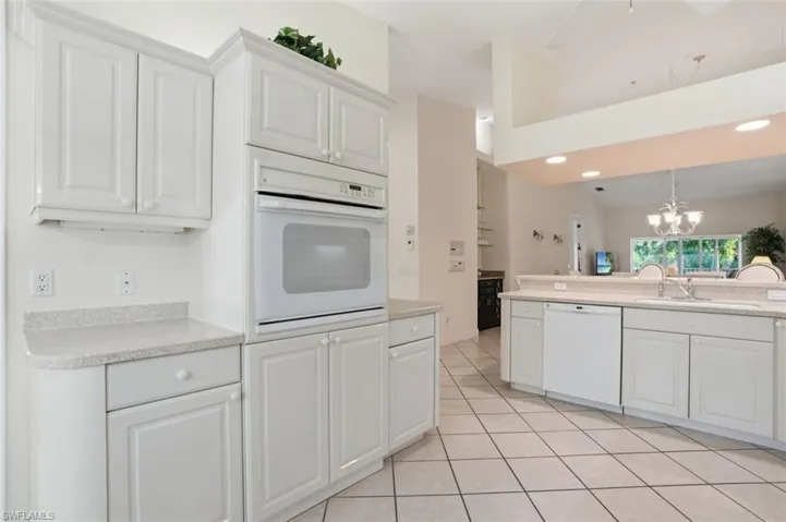 Kitchen featuring white cabinetry, light-toned countertops, a built-in oven, and a dishwasher