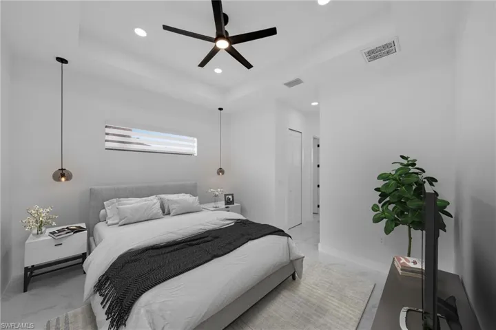Bedroom featuring light marble finish floors, a tray ceiling, a ceiling fan, and recessed lighting