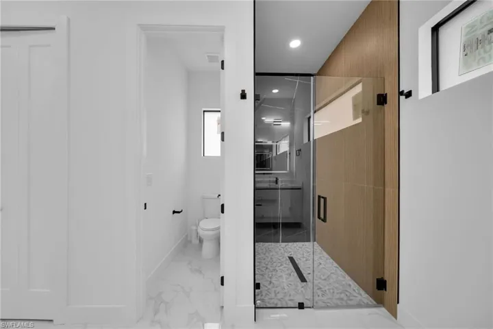 Full bath with a shower stall, light marble finish flooring, and recessed lighting