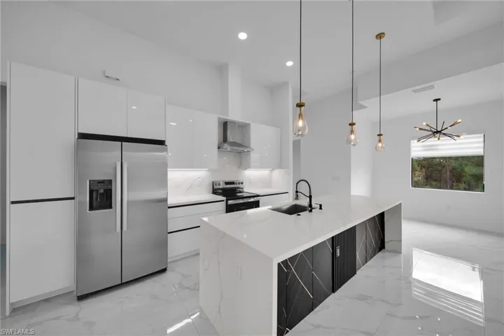 Kitchen featuring stainless steel appliances, light marble finish flooring, white cabinets, hanging light fixtures, and recessed lighting