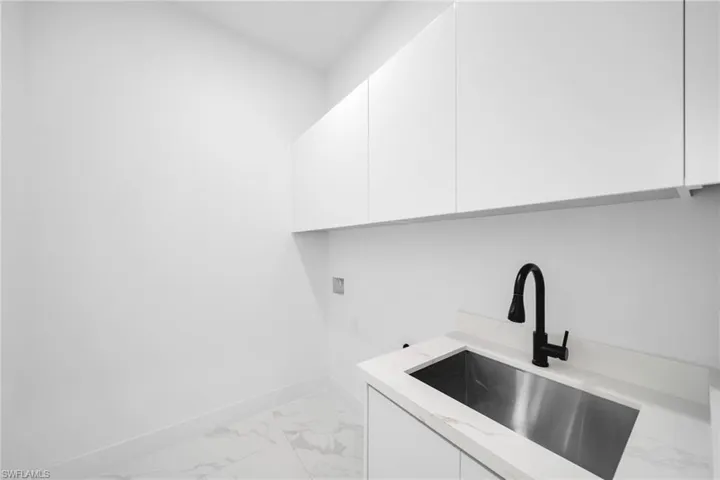 Laundry area featuring light marble finish floors, cabinet space, and washer hookup