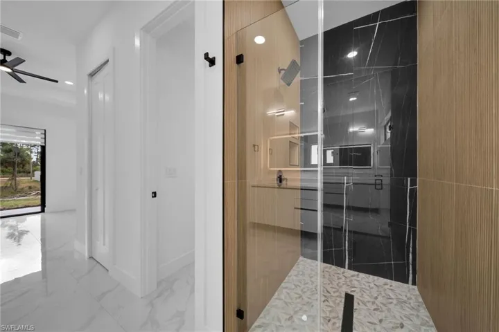 Bathroom with vanity, marble look tile flooring, a marble finish shower, a ceiling fan, and recessed lighting