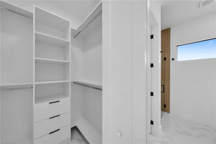Spacious closet featuring light marble finish flooring