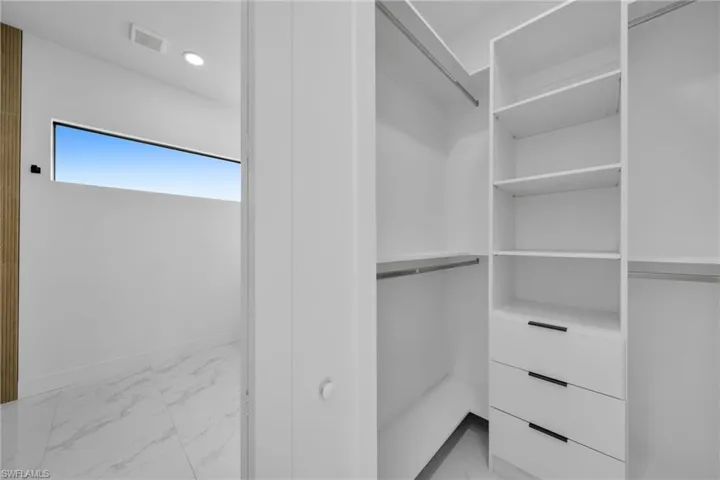 Spacious closet with light marble finish floors