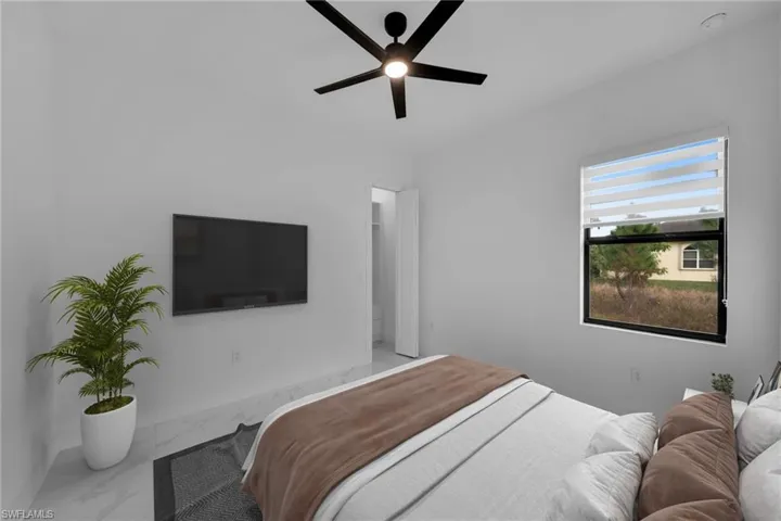 Bedroom with marble look tile flooring and a ceiling fan