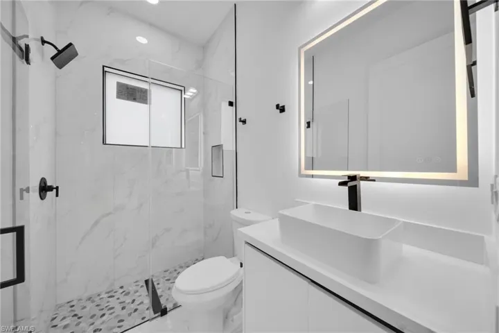 Bathroom with vanity, a marble finish shower, marble finish floors, and recessed lighting