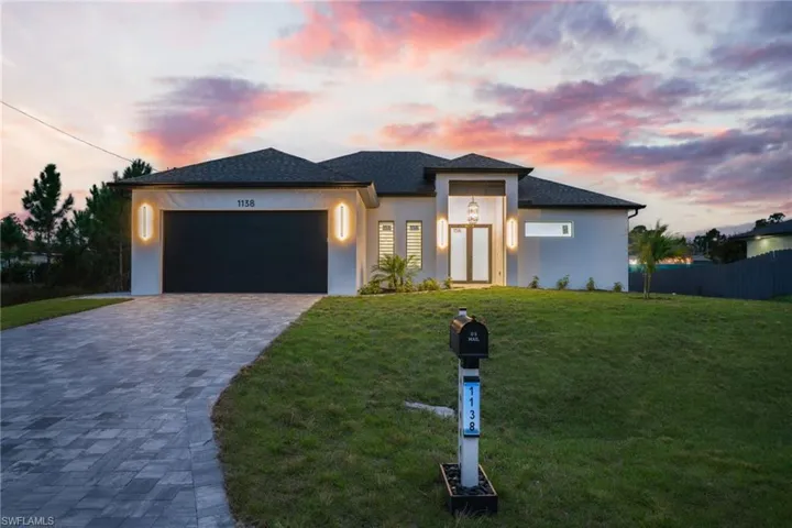 Prairie-style house with stucco siding, decorative driveway, and an attached garage
