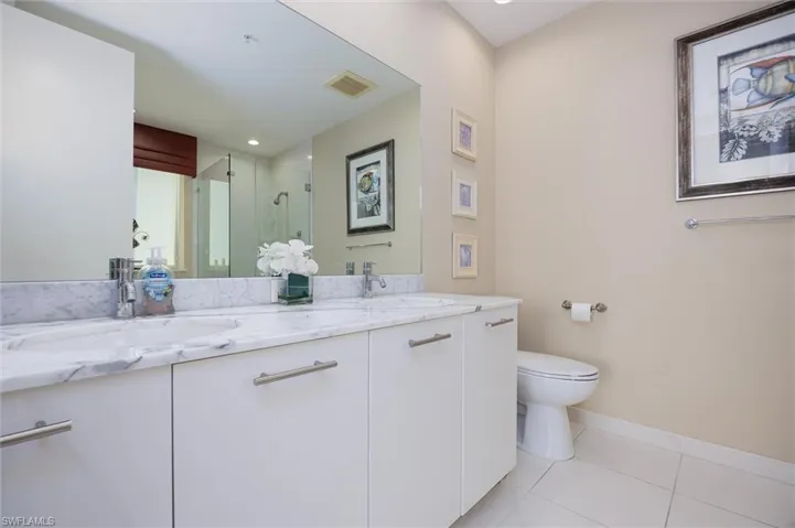 Full bathroom with a stall shower, double vanity, and light tile patterned floors