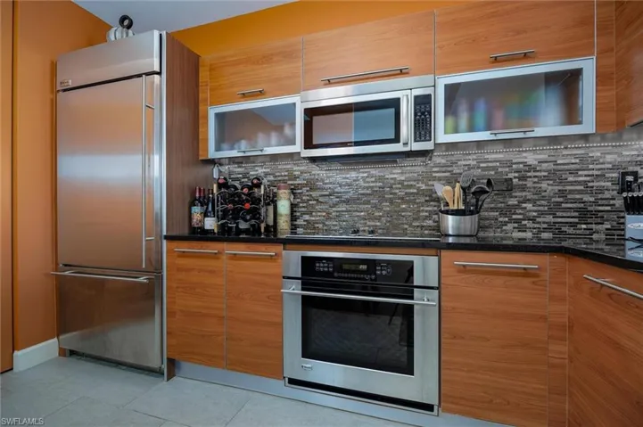 Kitchen featuring stainless steel appliances, dark stone countertops, wood finish cabinets, and modern cabinets