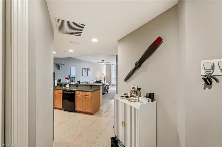 Kitchen featuring dark countertops, brown cabinetry, recessed lighting, dishwasher, and light tile patterned floors