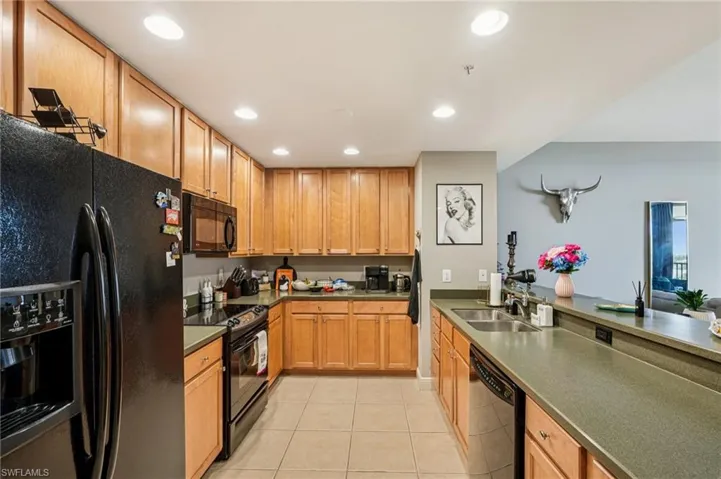 Kitchen featuring black appliances, recessed lighting, light tile patterned floors, brown cabinets, and dark countertops