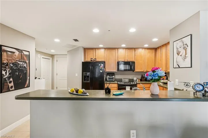 Kitchen featuring black appliances, recessed lighting, dark countertops, a peninsula, and light tile patterned floors