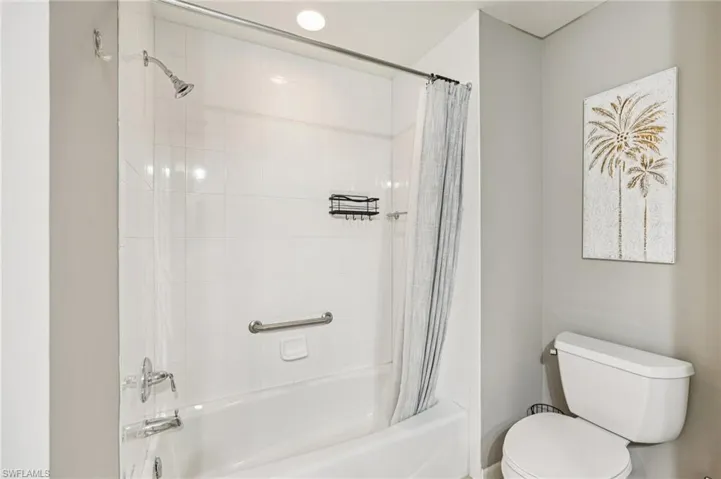 Bathroom featuring shower / bath combination with curtain and toilet