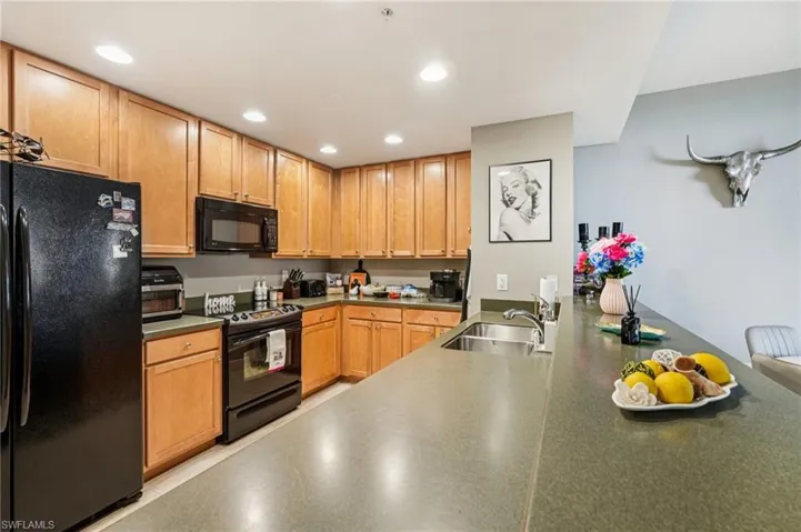 Kitchen featuring black appliances, dark countertops, recessed lighting, and a peninsula