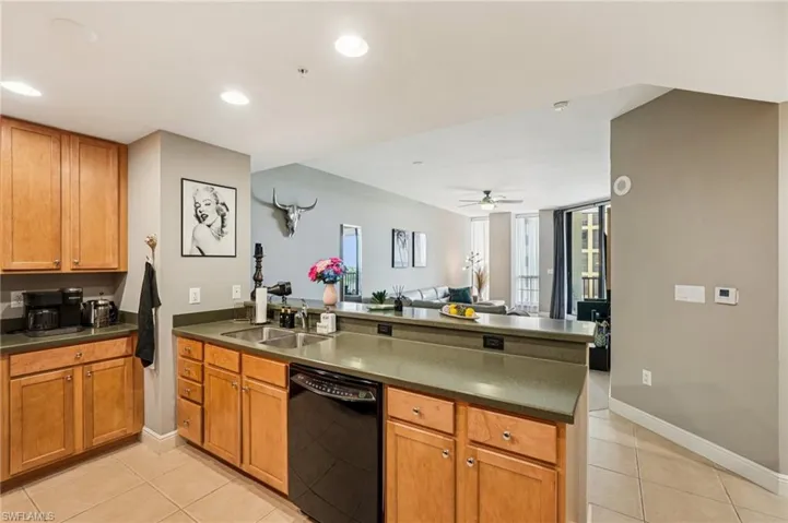Kitchen with a peninsula, brown cabinets, dishwasher, open floor plan, and light tile patterned floors