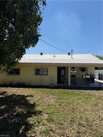 View of front of home with a front yard, a metal roof, washer / dryer, and a patio