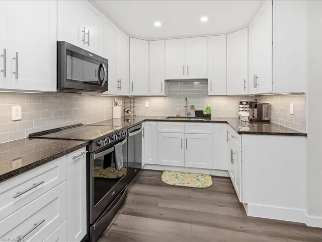 Kitchen featuring electric range oven, dark stone counters, and white cabinets