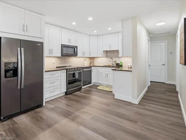 Kitchen with appliances with stainless steel finishes, white cabinets, dark wood-style flooring, and recessed lighting
