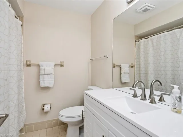 Bathroom featuring curtained shower, vanity, and light tile patterned flooring
