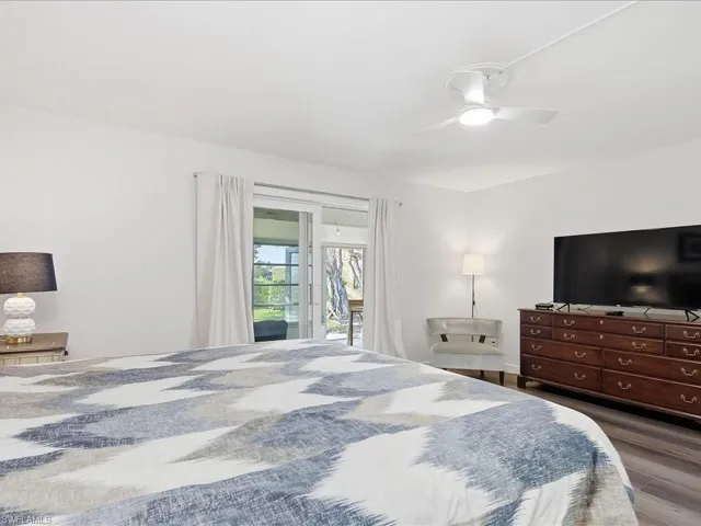Bedroom with access to exterior, a ceiling fan, and dark wood finished floors
