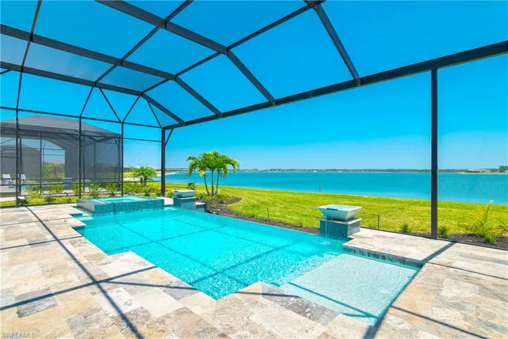Integrated pool / hot tub with a lawn, glass enclosure, a water view, a sunroom, and a patio
