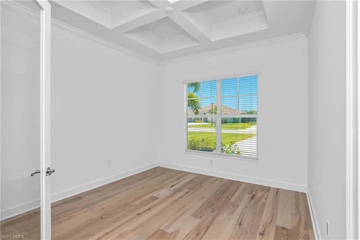 Unfurnished room with coffered ceiling, light wood finished floors, and crown molding