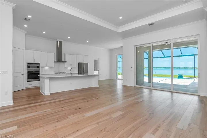 Kitchen featuring open floor plan, a center island with sink, white cabinetry, light wood finished floors, and recessed lighting