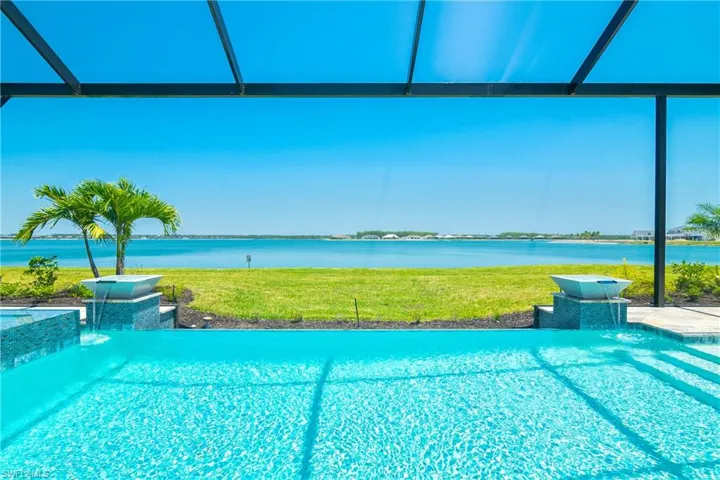 Swimming pool featuring a yard, glass enclosure, a water view, and a patio