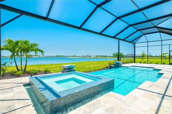 Combined pool / hot tub with a yard, a patio area, a water view, and a lanai