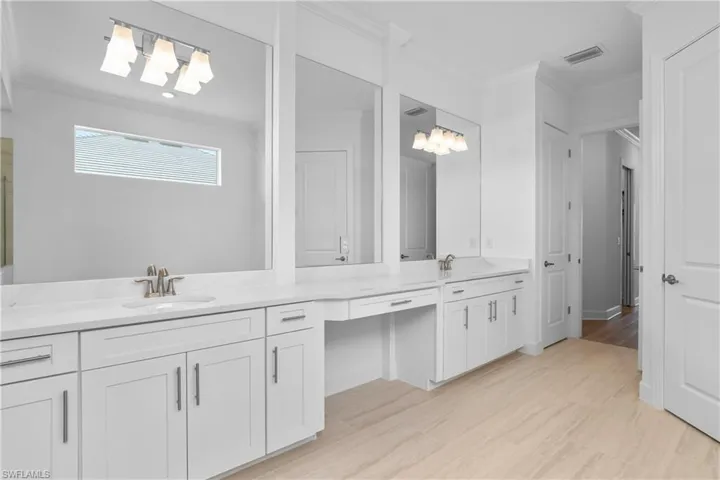 Bathroom featuring ornamental molding, double vanity, and light wood finished floors