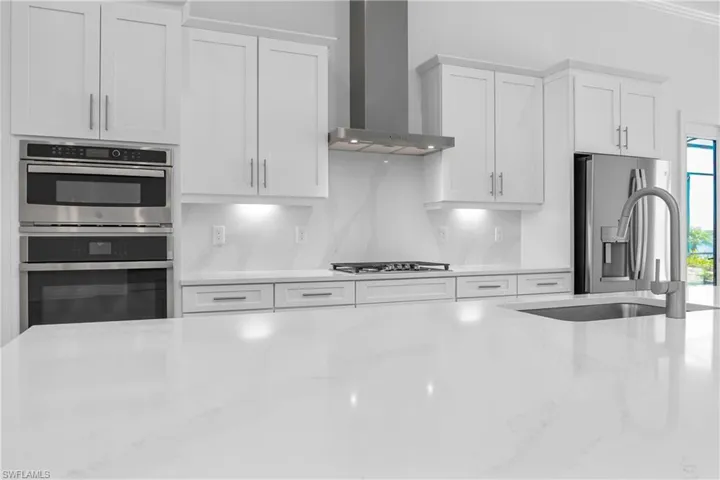Kitchen featuring white cabinets, light stone countertops, and stainless steel appliances