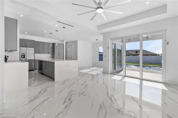 Unfurnished living room featuring recessed lighting, a raised ceiling, light marble finish flooring, and a ceiling fan