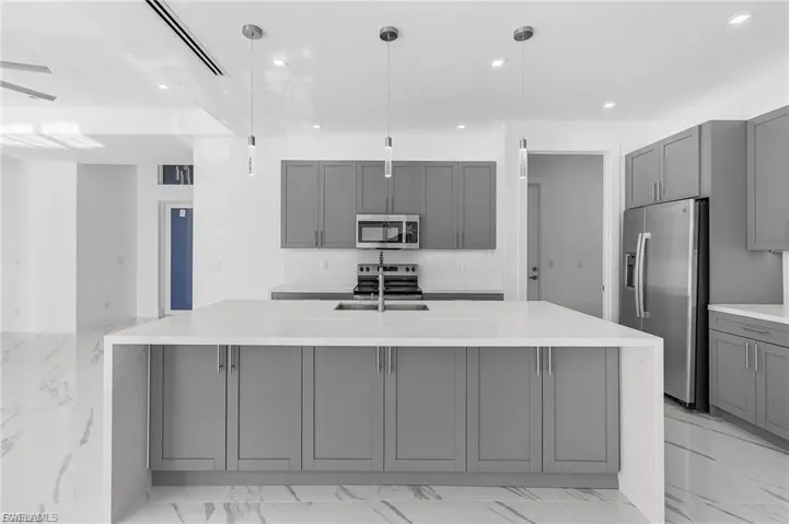 Kitchen featuring gray cabinetry, light stone countertops, light marble finish floors, appliances with stainless steel finishes, and recessed lighting