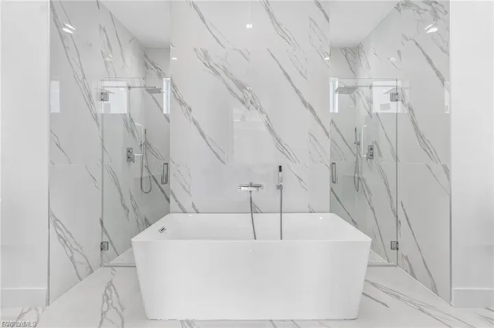 Bathroom with a soaking tub, a marble finish shower, and marble tiled flooring