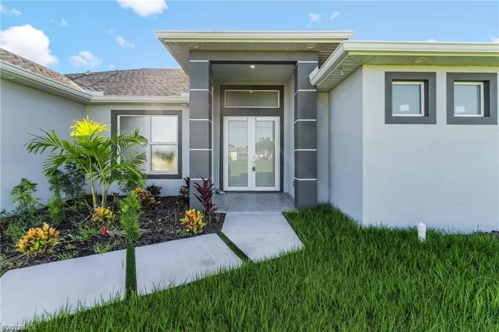 Entrance to property with stucco siding, a yard, and french doors