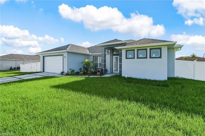 View of front of home with stucco siding, an attached garage, and driveway