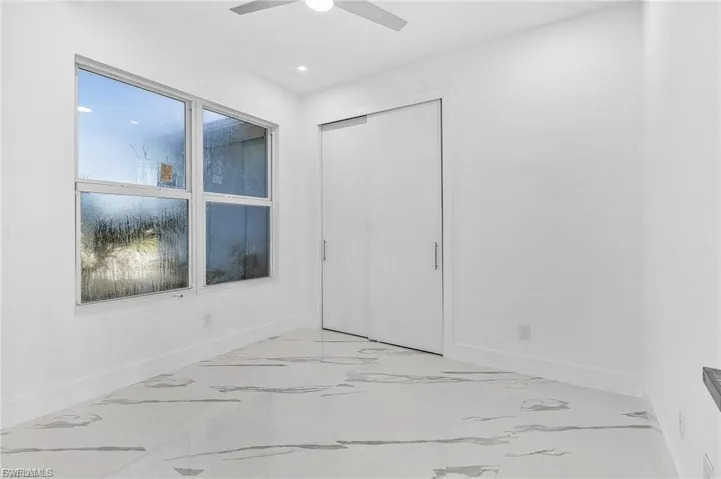 Unfurnished bedroom featuring ceiling fan, a closet, and light marble finish flooring