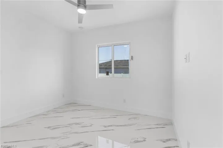 Empty room featuring light marble finish floors and ceiling fan