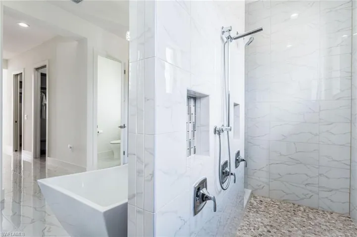 Spacious bathroom featuring a freestanding soaking tub and a walk-in shower with pebble flooring