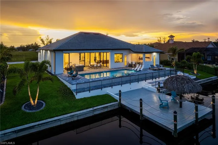 Waterfront residence featuring a spacious patio, private swimming pool, expansive sliding glass doors, a manicured lawn, and a private dock