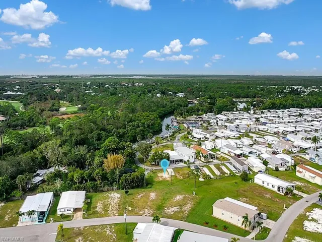 Aerial view of property and surrounding area featuring nearby suburban area and a heavily wooded area