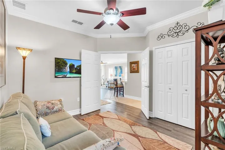 Living room with hardwood / wood-style floors, crown molding, and ceiling fan