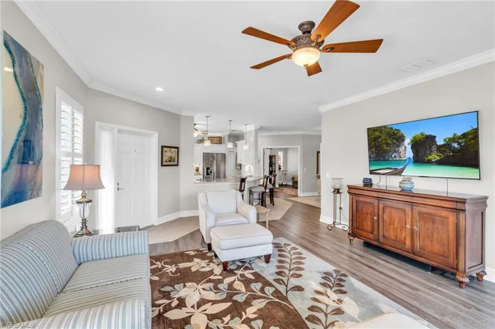 Living room with crown molding, light wood-type flooring, and ceiling fan