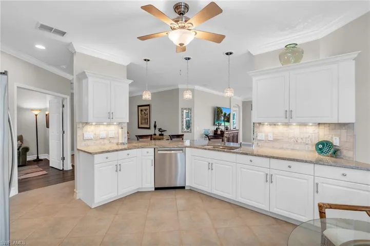 Kitchen with white cabinetry, backsplash, stainless steel appliances, and ornamental molding