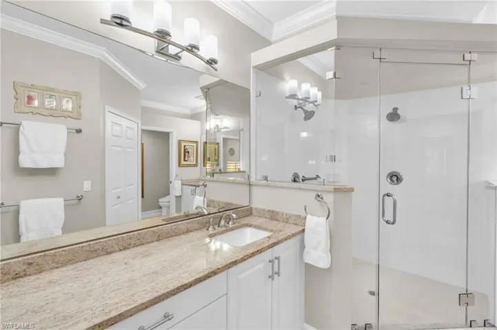 Bathroom with vanity, an enclosed shower, toilet, and crown molding