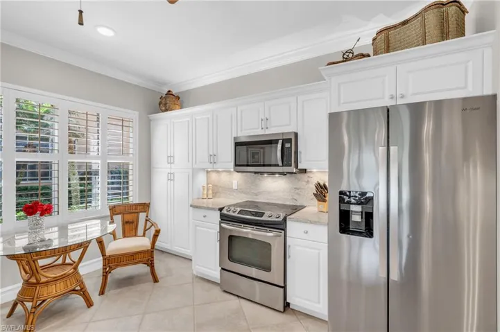Kitchen with a wealth of natural light, appliances with stainless steel finishes, and white cabinetry