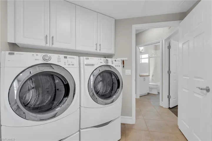 Laundry room with cabinets, independent washer and dryer, and light tile patterned floors
